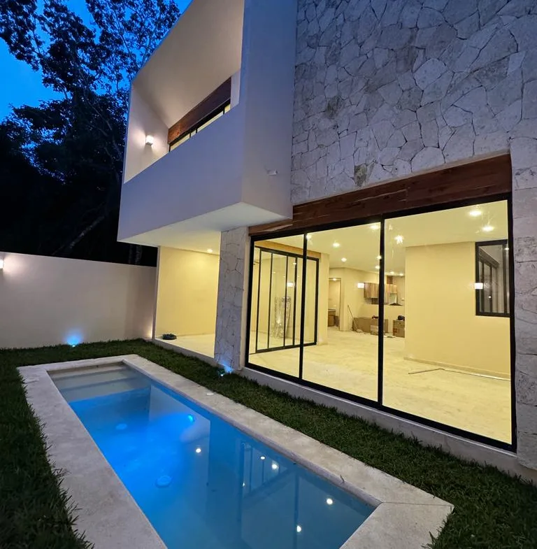 Backyard pool and glass doors at night – 3-bedroom house in Residencial Valenia, Playa del Carmen