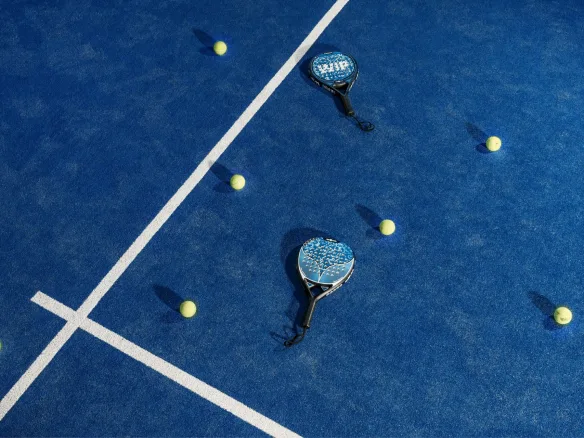 Paletas y pelotas de pádel sobre una cancha azul